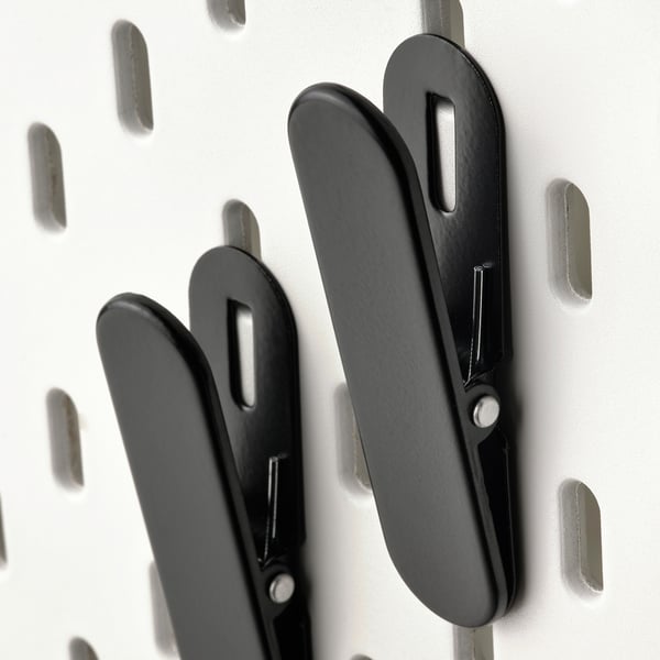 Black metal hooks mounted on a white pegboard, displaying sturdy construction and sleek design, suitable for organising items efficiently.