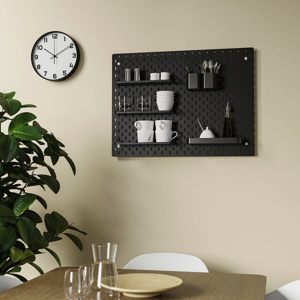 Black pegboard wall organiser with cups, glasses, and plant.