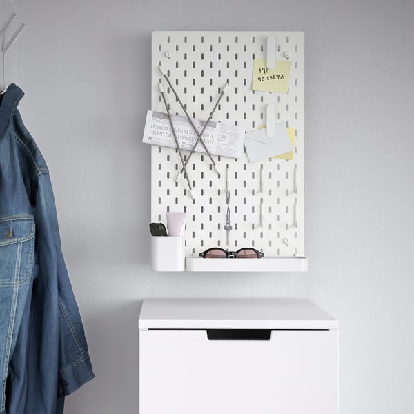 White SKÅDIS pegboard with accessories and denim jacket. Organises small items like keys, notes, and more.