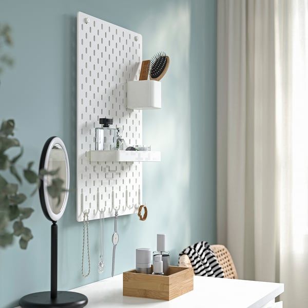 Wall-mounted SKÅDIS pegboard organises jewellery, beauty items with shelves and hooks.