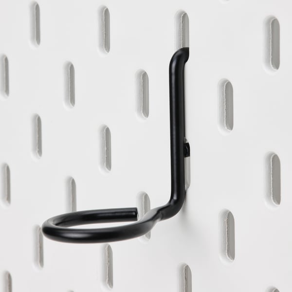 Black metal hook securely attached to white pegboard, showcasing sturdy design and quality.