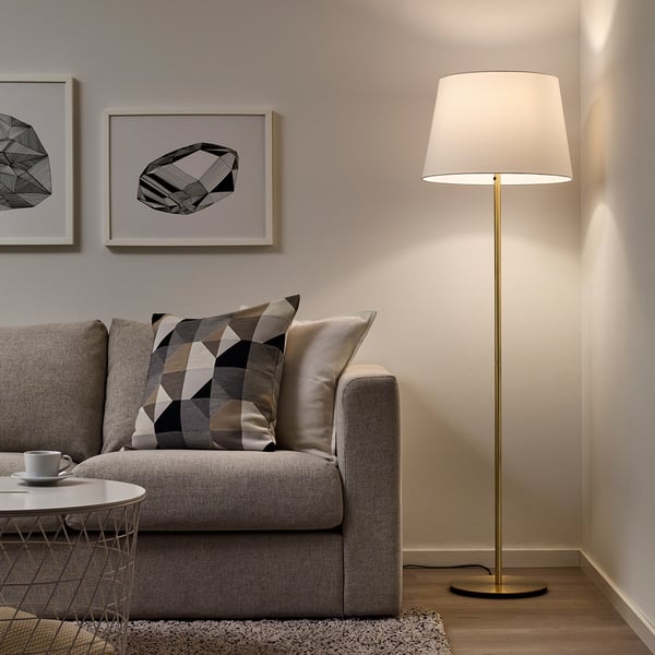 Minimalist living room with grey sofa, modern floor lamp, cream lamp shade, coffee table, and abstract wall art.