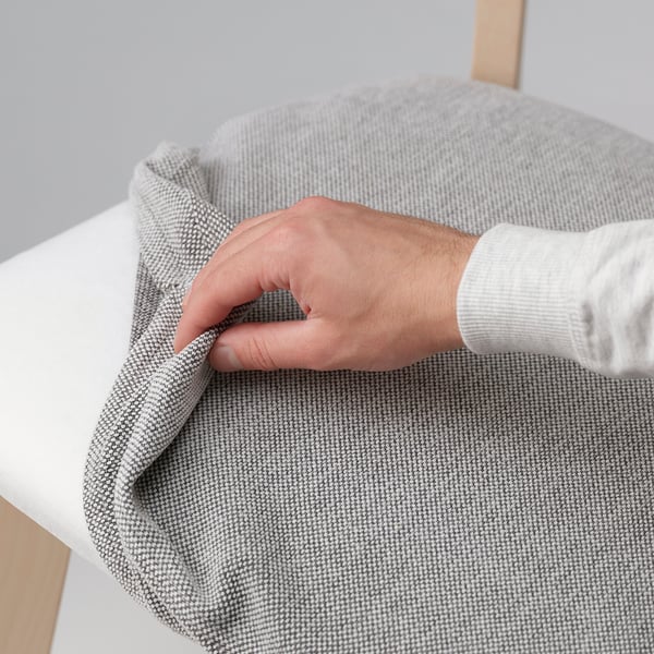 Person holding extendable tablecloth, revealing wooden table beneath.