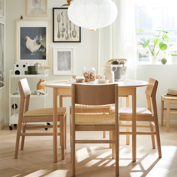 Bright, modern dining set with light wood chairs & round table, featuring woven seats & butterfly leaf extension, perfect for small spaces.