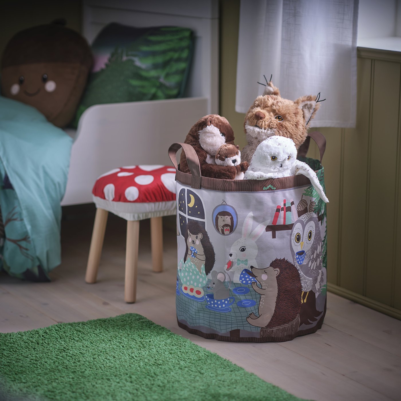 SKOGSDUVA toy bag with plush toys on a green rug, next to a childs bed, showcasing enchanted forest design.