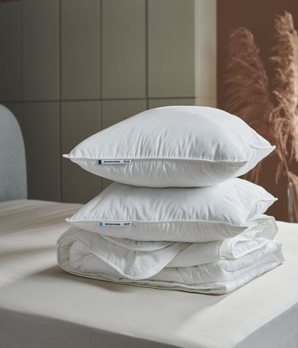 Stack of three white pillows on a bed, labelled SKOGSFRÄKEN.