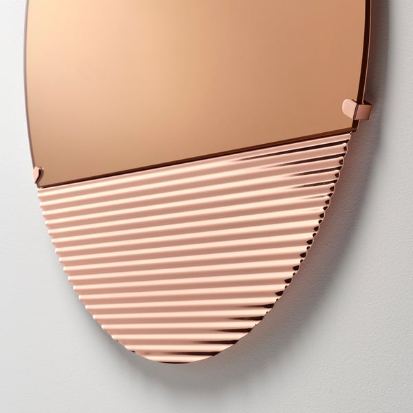SKOGSGRÄNSEN mirror, rose-gold toned, wavy bottom reflection, mounted on white wall.