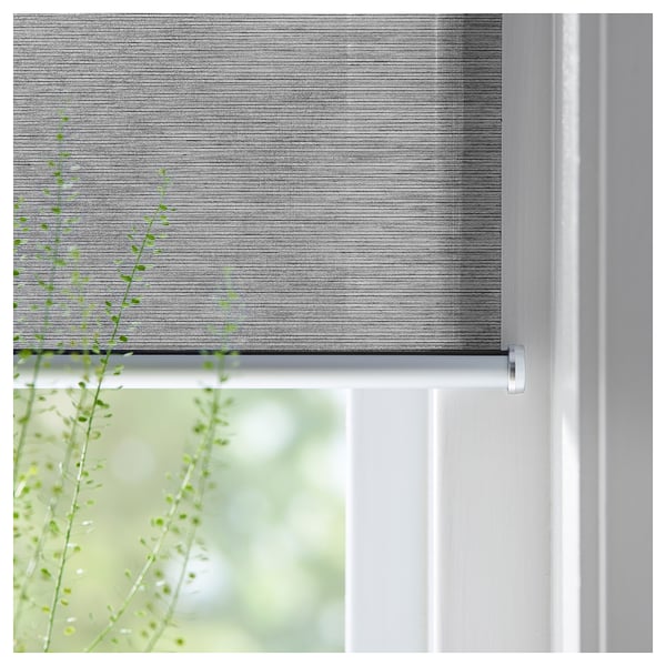 SKOGSKLÖVER roller blind, grey, cordless, mounted on white window.