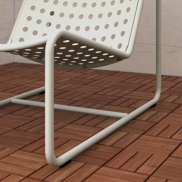 White metal patio chair with perforated seat and backrest on wooden deck.