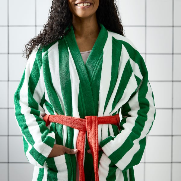 Person in green and white striped robe with red belt, hands in pockets.