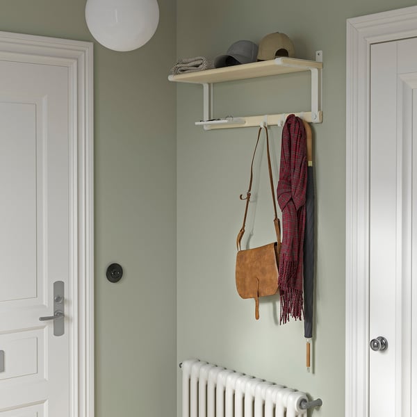 Wall-mounted SKOMAKARE organiser with shelf, hooks, tray. Hangs scarf, purse, hats. Between doors, green wall, below radiator.