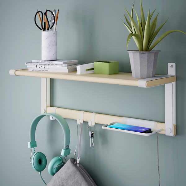 Wall-mounted shelf with hooks holding headphones and keys, tray with a phone, and potted plant with books and stationery on top.