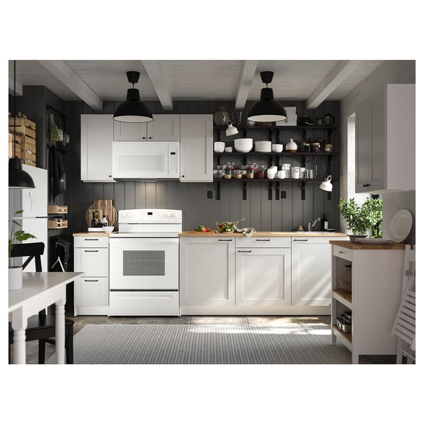 Modern kitchen with white cabinets, black pendant lights, and black and white chequered oven door.