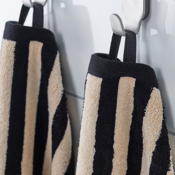 Two striped towels hang on hooks. Black and beige stripes, soft and absorbent.