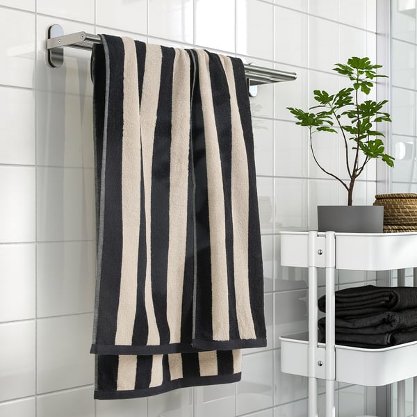 Black & beige striped towel on metal rack in clean bathroom.
