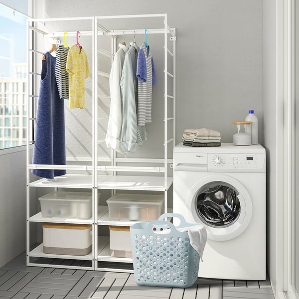 Laundry area with white washing machine, drying rack holding clothes, and blue basket for dirty laundry.