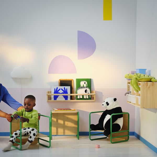 Child in green chair with panda toy & books.