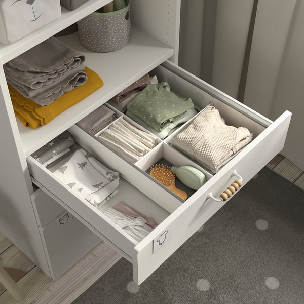 Open drawer of SMÅSTAD bookcase showing neatly folded clothes and personal care items, demonstrating organised storage in small spaces.