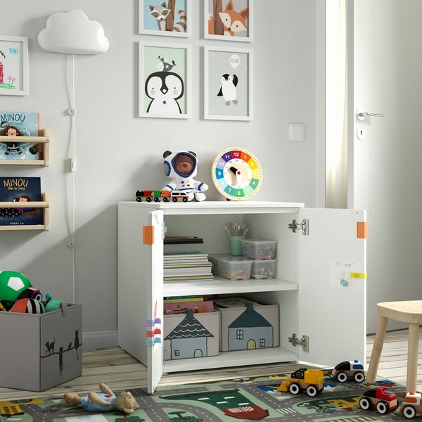 Childs room with white storage cabinet, toys, books, and colourful clock.