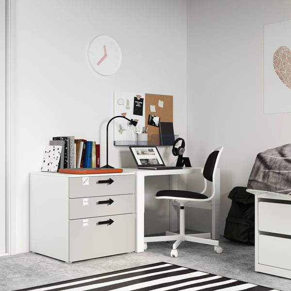White kids desk with drawers, books, laptop, chair, clock, and backpack. Includes storage and study setup.
