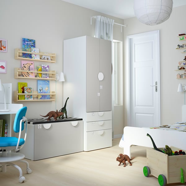 Childs room with white furniture: desk, chair, wardrobe, shelves, and storage boxes. Dinosaur toys displayed.
