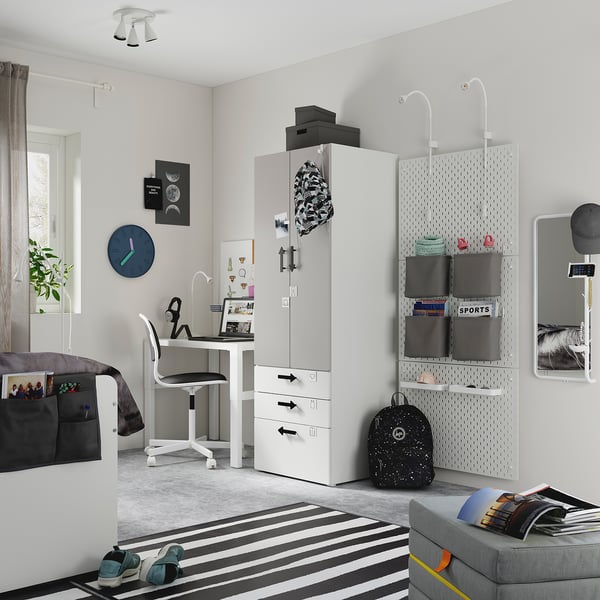 Modern teen bedroom with a white SMÅSTAD wardrobe, grey bed, black-and-white decor. Includes a desk, pegboard, and striped rug.