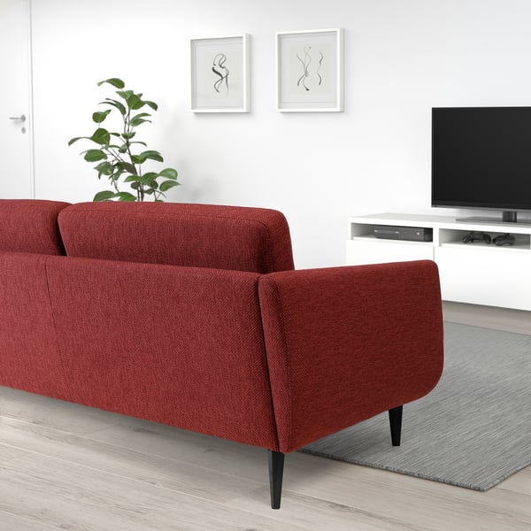 A modern, red sofa with black legs, offering comfortable seating and easy access for cleaning.