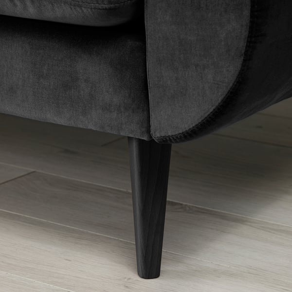 Dark grey sofa with tapered wooden legs on a light wooden floor.