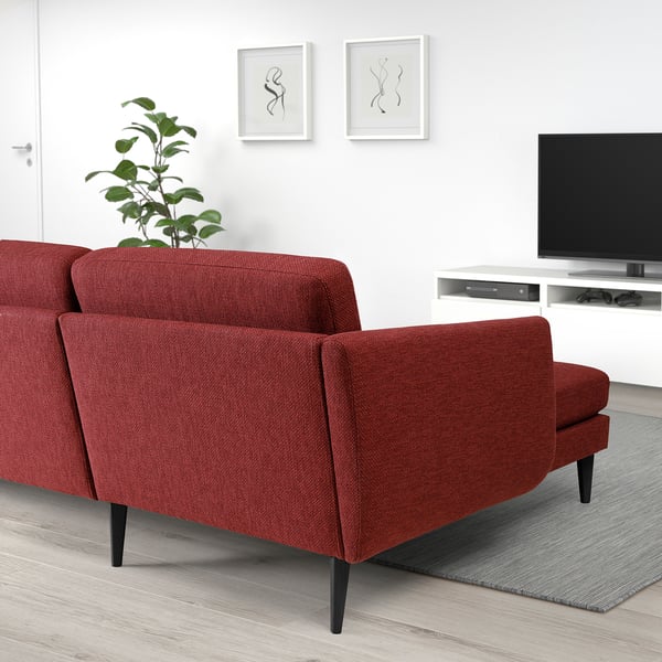 Red retro SMEDSTORP sofa with curved edges, cone legs, foam cushions. Minimalist decor, tv, artwork.