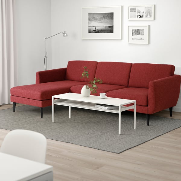 Red retro-style sofa with soft shapes & cone legs in minimalist living room.