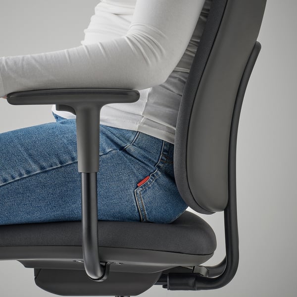 Person sitting in SMÖRKULL office chair, showing adjustable armrest.