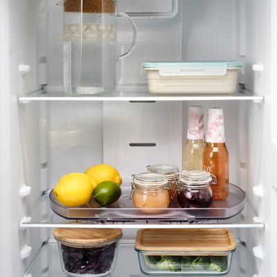 Fridge shelf with rotating tray holding fruits, jars, and bottles, promoting easy access.