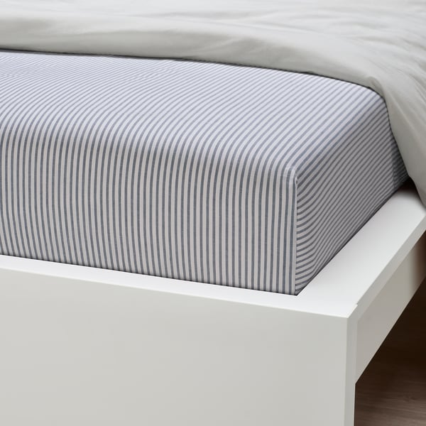 Striped bed sheet on white bed, neatly fitted, showcasing high quality cotton and elastic edge.