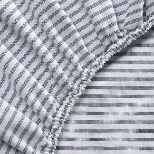 Grey striped bedsheet corner with ruffled edge, high-quality cotton, visible stitching detail.