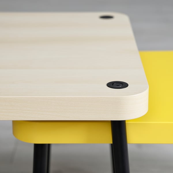 Two modern, light wooden nesting tables with black fixtures and bright yellow bases, shown from a side angle.