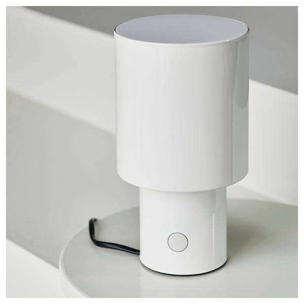 A sleek, white table lamp with a circular, on/off button. Elegant design, modern aesthetic.