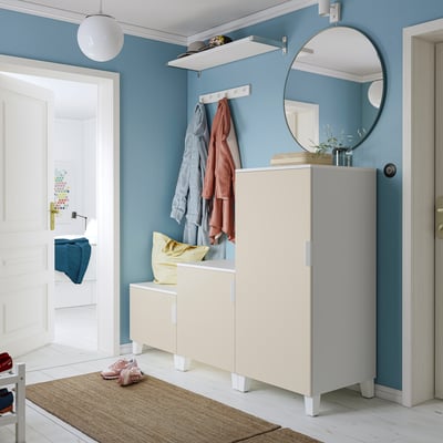 Modern entryway: blue walls, white furniture, round mirror, cabinet with mirror top & yellow cushion.