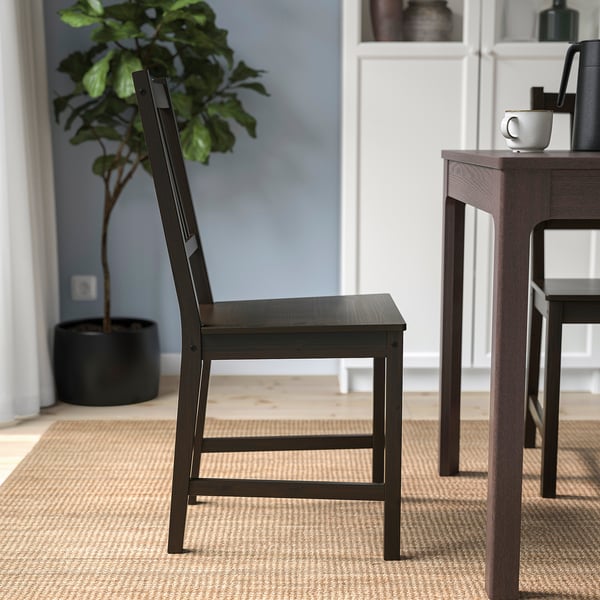A sturdy wooden chair with a high back, ideal for everyday use, placed near a table.