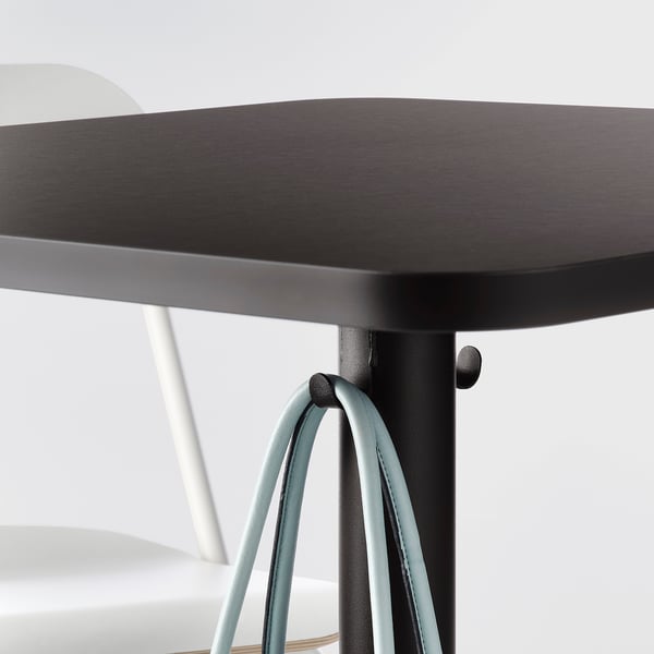 Black square bar table with steel legs, adjustable feet for stability.
