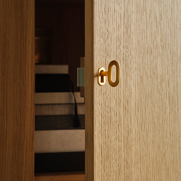 Close-up of a light wood cabinet with a gold-colored lock and key, showcasing high-quality finish and sleek design.