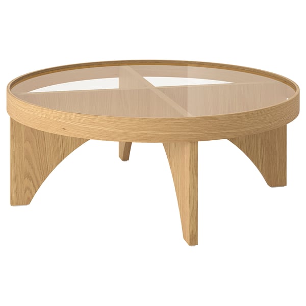 This image the STOCKHOLM 2025 coffee table. Its round, light brown with a glass top. Modern scandinavian design with sleek, elegant lines.