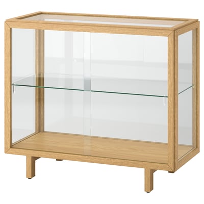 STOCKHOLM 2025: lightwood, glass-fronted cabinet with 2 adjustable shelves and feet for uneven floors.