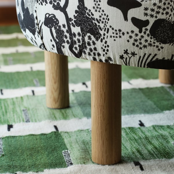 Rounding wooden legs support a cushioned seat, part of STOCKHOLM 2025 pouffe set.