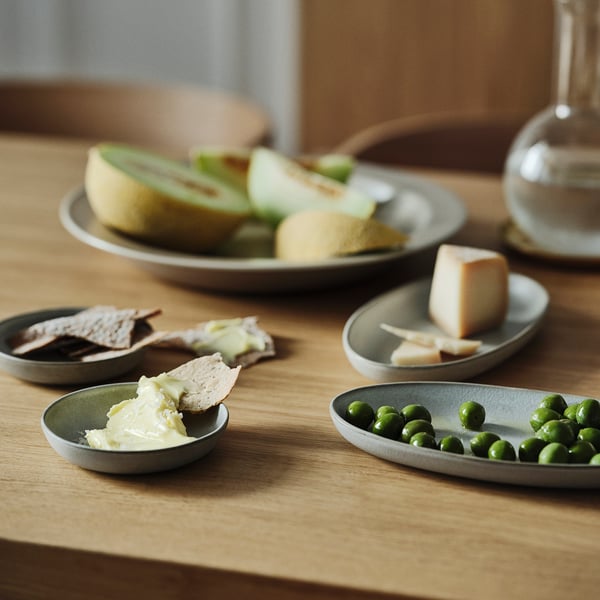 Small plates with bread, cheese, peas, and sauce on wooden table.
