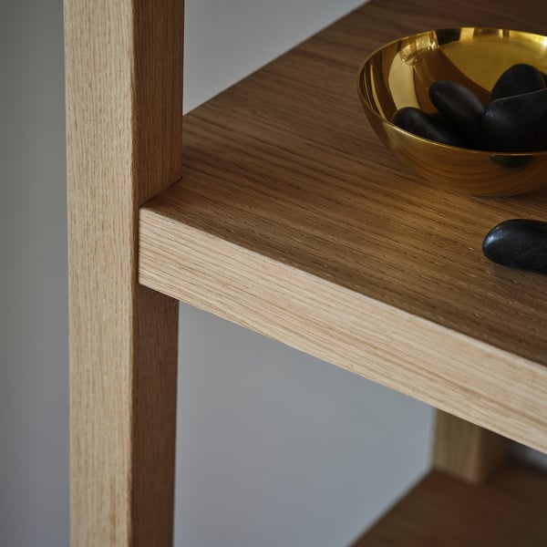 Well-crafted oak shelf with smooth veneer, showcasing natural grain. Golden bowl with black pebbles sits elegantly on wide shelf.