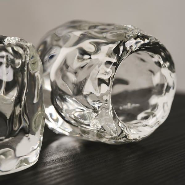 Glass ice cube candle holder, reflections on dark surface.