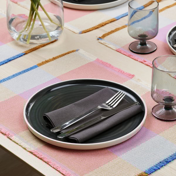 Striped table setting with place mat, plate, cutlery, and glasses.