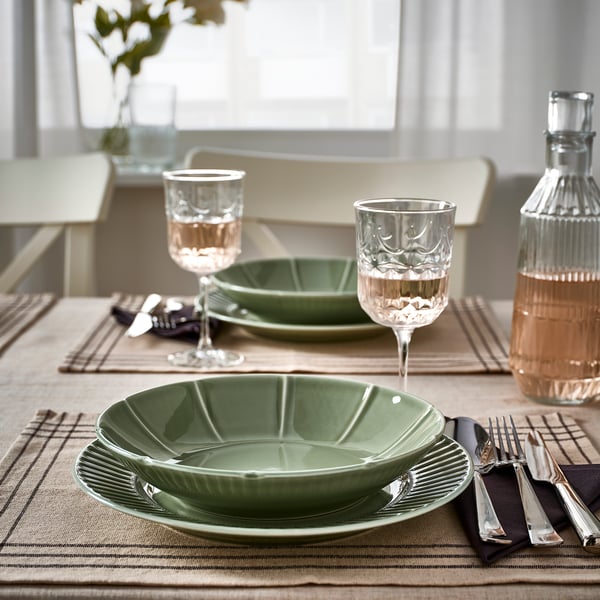 Green STRIMMIG bowls and plates on table with cutlery and glasses.
