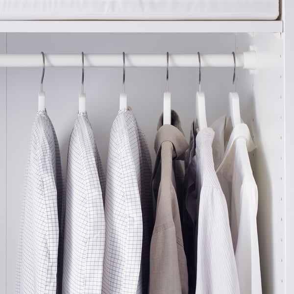 White closet with three grey-checkered clothes covers protecting garments from dust.