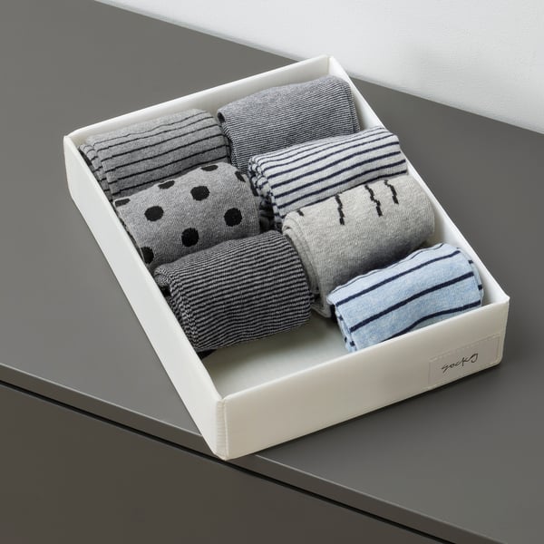 Box of folded socks with varied patterns neatly organised.